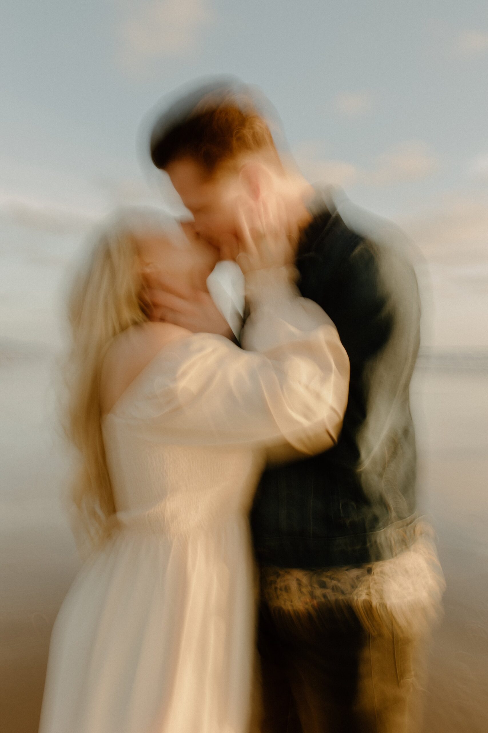 blurry image of woman kissing man on beach in Oregon, Oregon film couples photographer