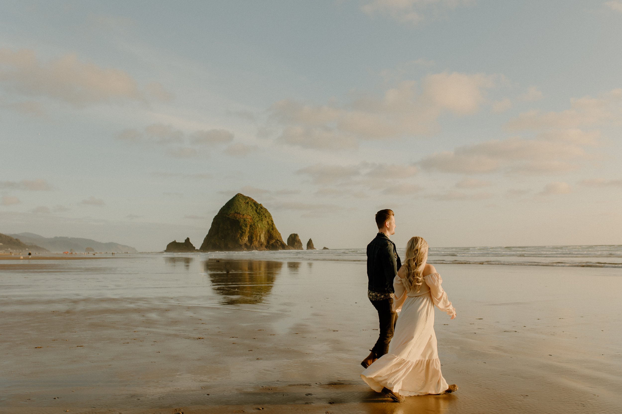 couple holding hands while walking on beach in Oregon