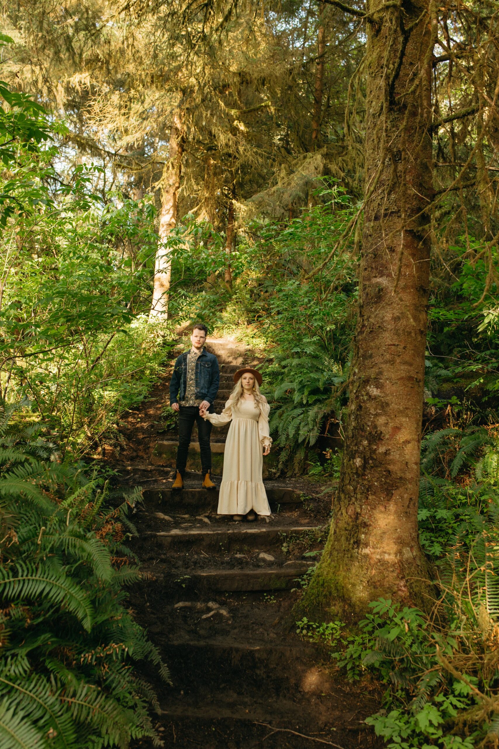 man and woman posing on stairs in forest near Oregon beach