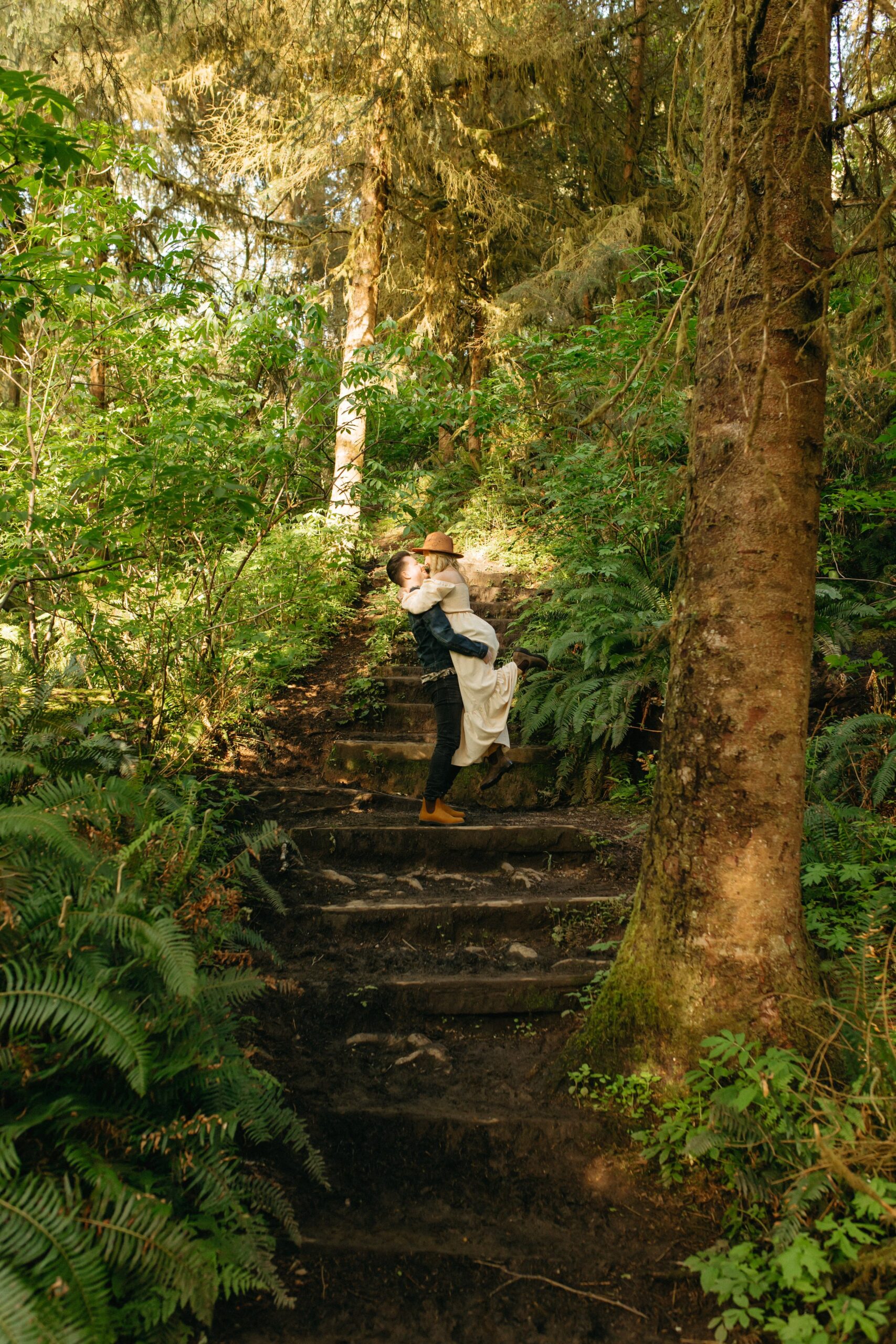 Man lifting woman on stairs in the middle of the forest near Oregon beach
