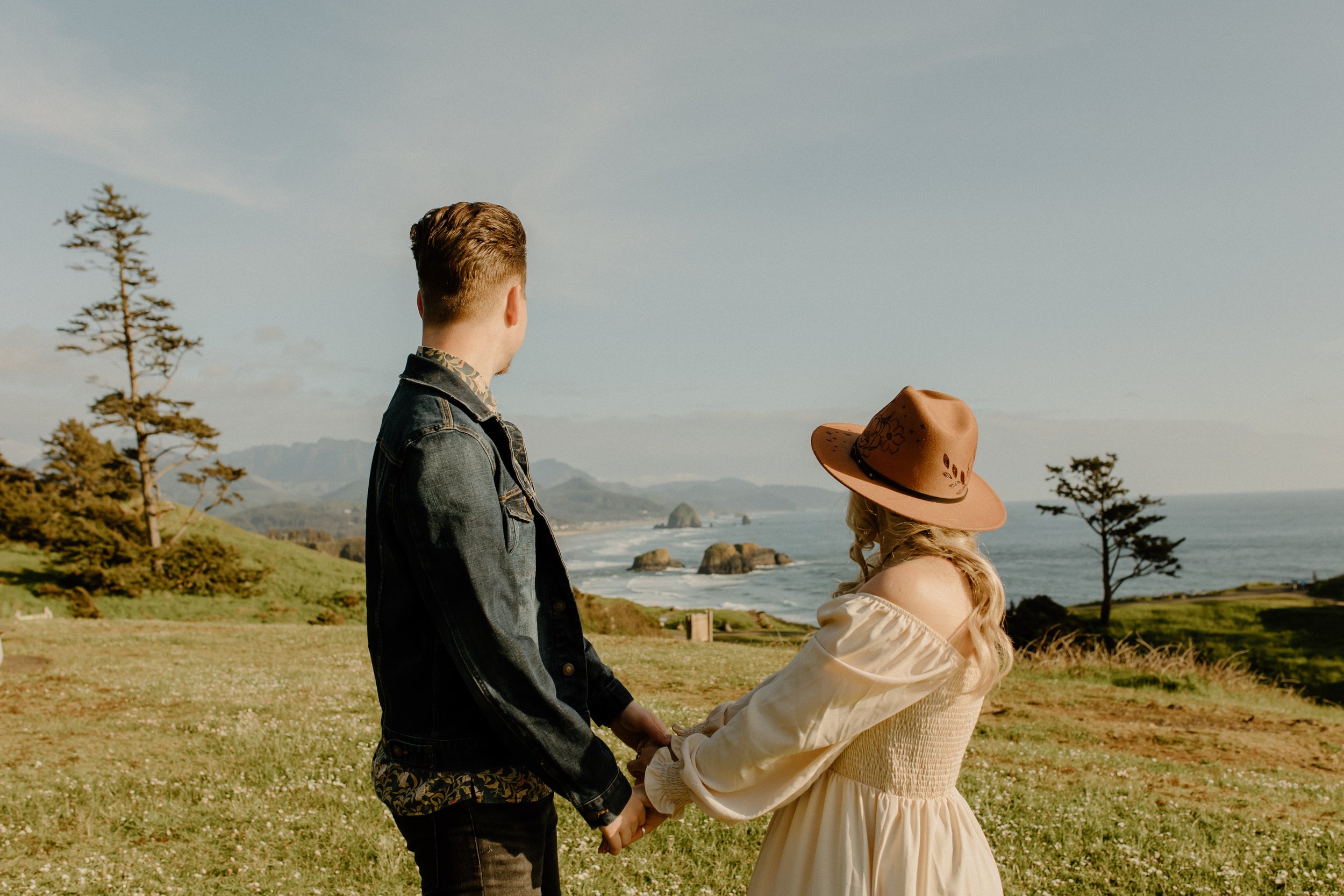 couple holding hands overlooking cliff by ocean, gorgeous meadow views, Oregon couples photographer