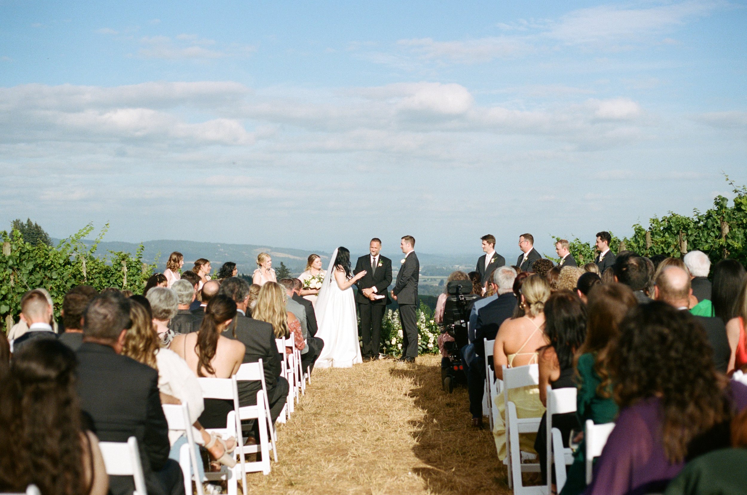 wedding ceremony with blue sky and clouds in background while bride and groom get married. Oregon coast wedding photographer