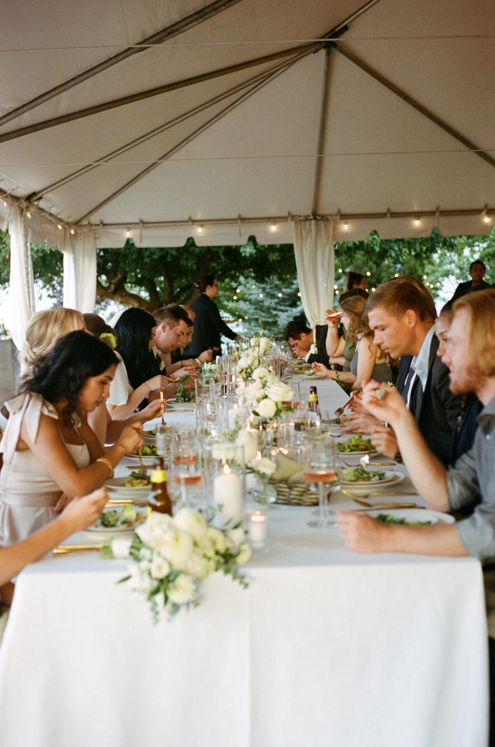 wedding reception under white wedding tent with wedding table decor and flower centerpieces. Oregon film wedding photographer