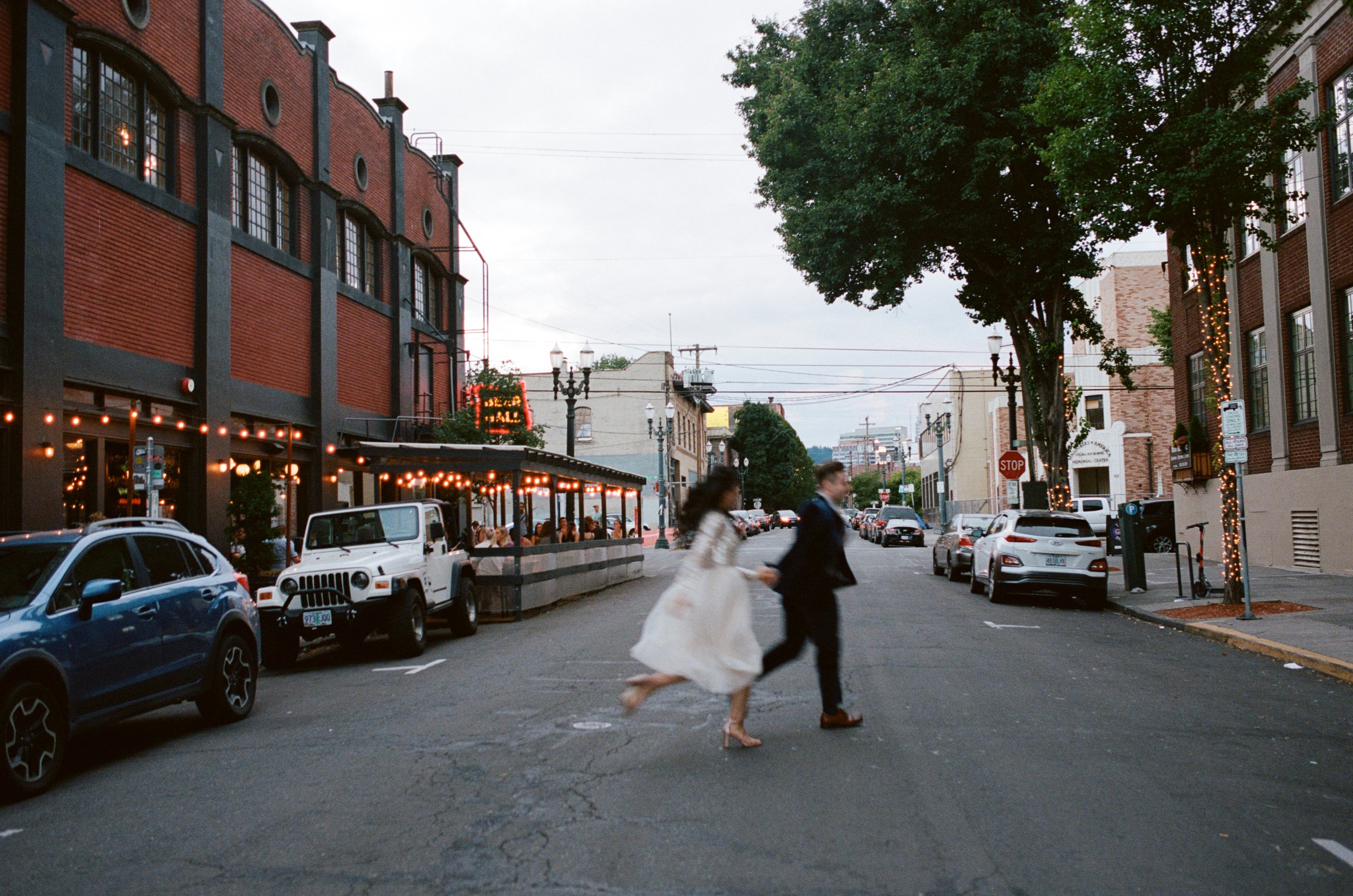 man and woman running through street after wedding ceremony. Wedding film photography, oregon