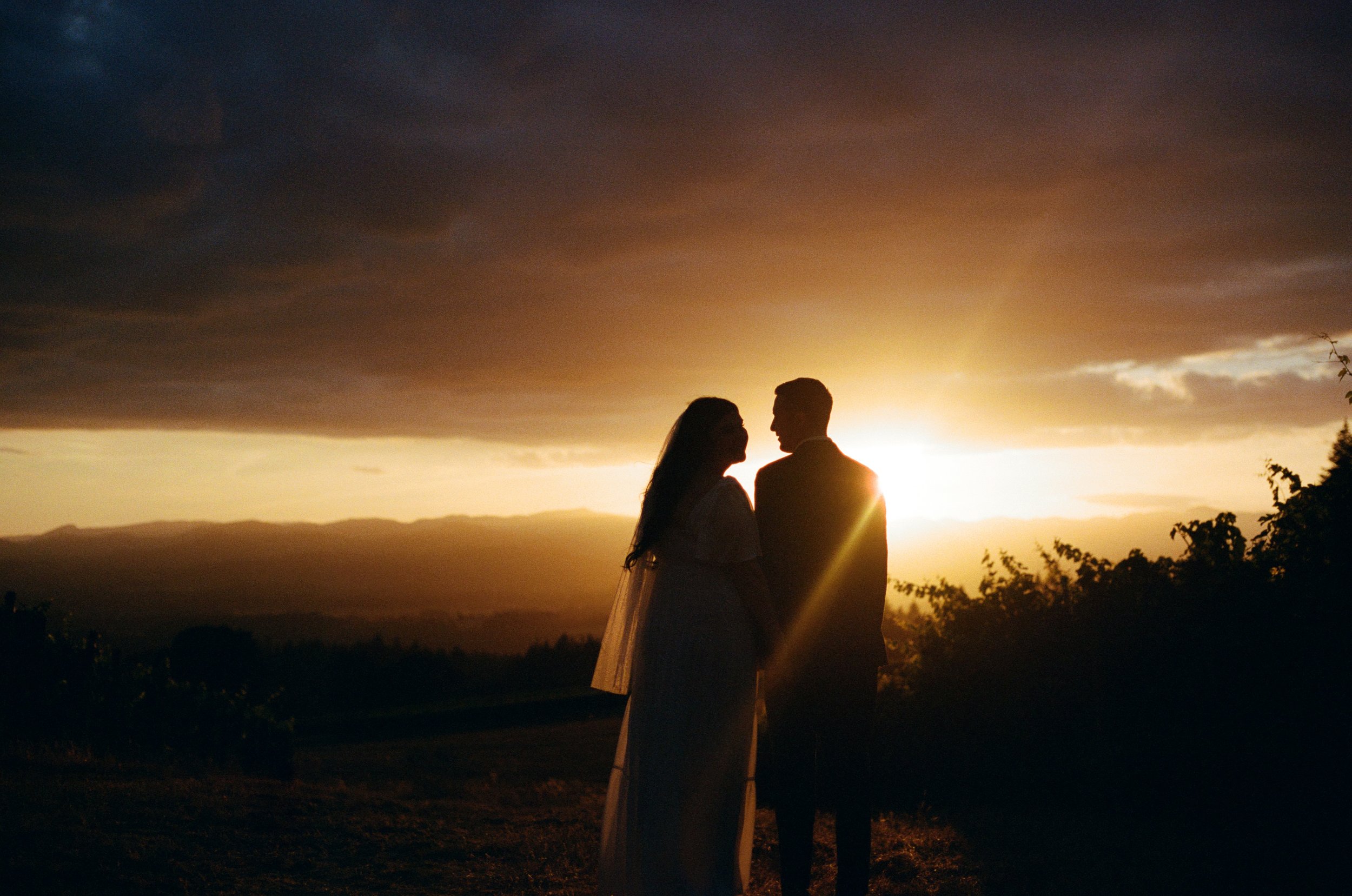 man and woman looking at eachother with sunset in front of them, film wedding photography