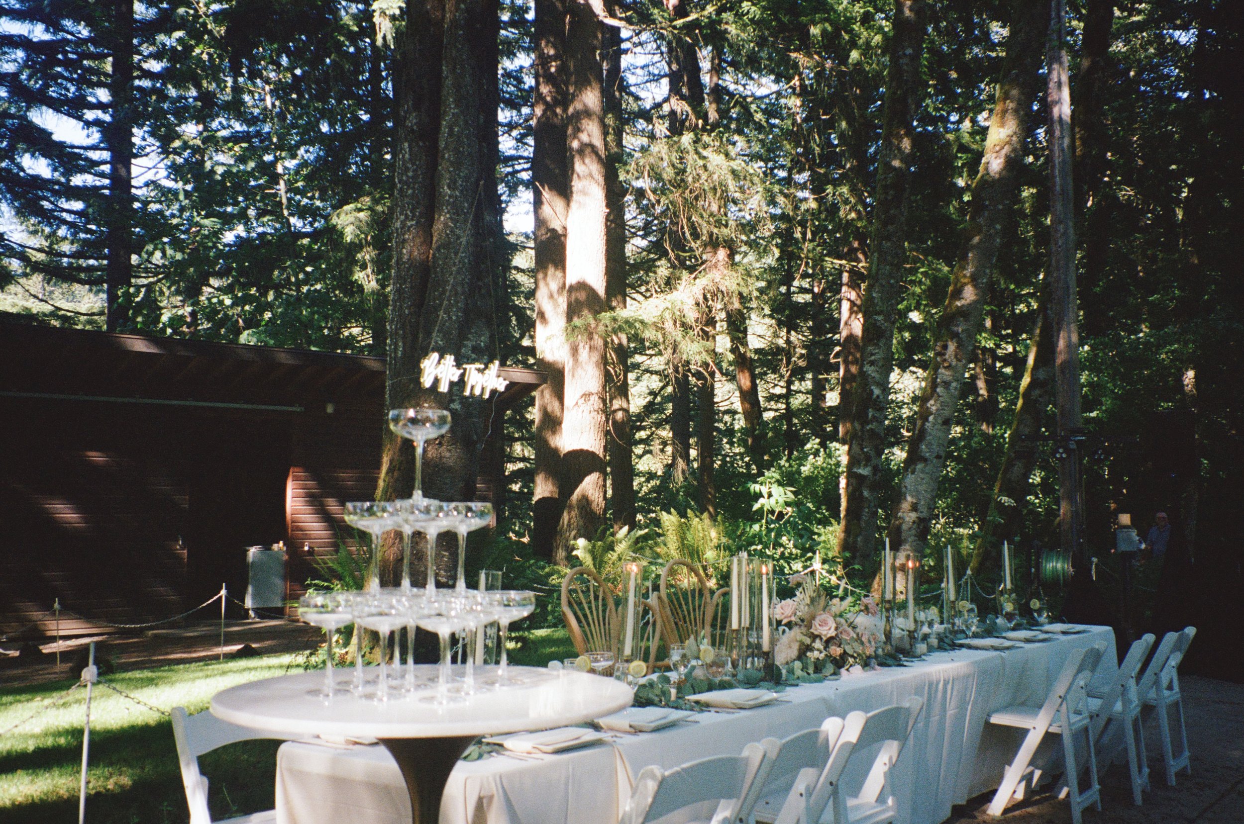 champagne tower and wedding reception table with wedding decorations with a backdrop of trees. Oregon coast wedding film photographer