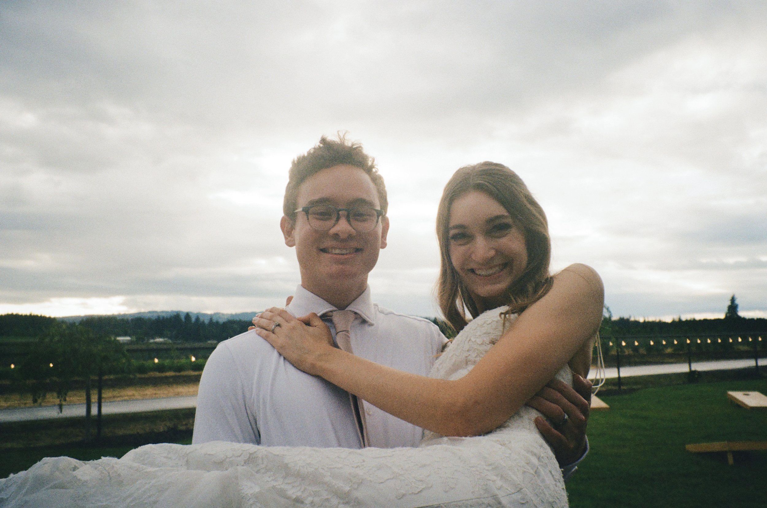 film photo of bride and groom. groom holding bride in arms while smiling at photo. Film Photography from Oregon wedding photographers