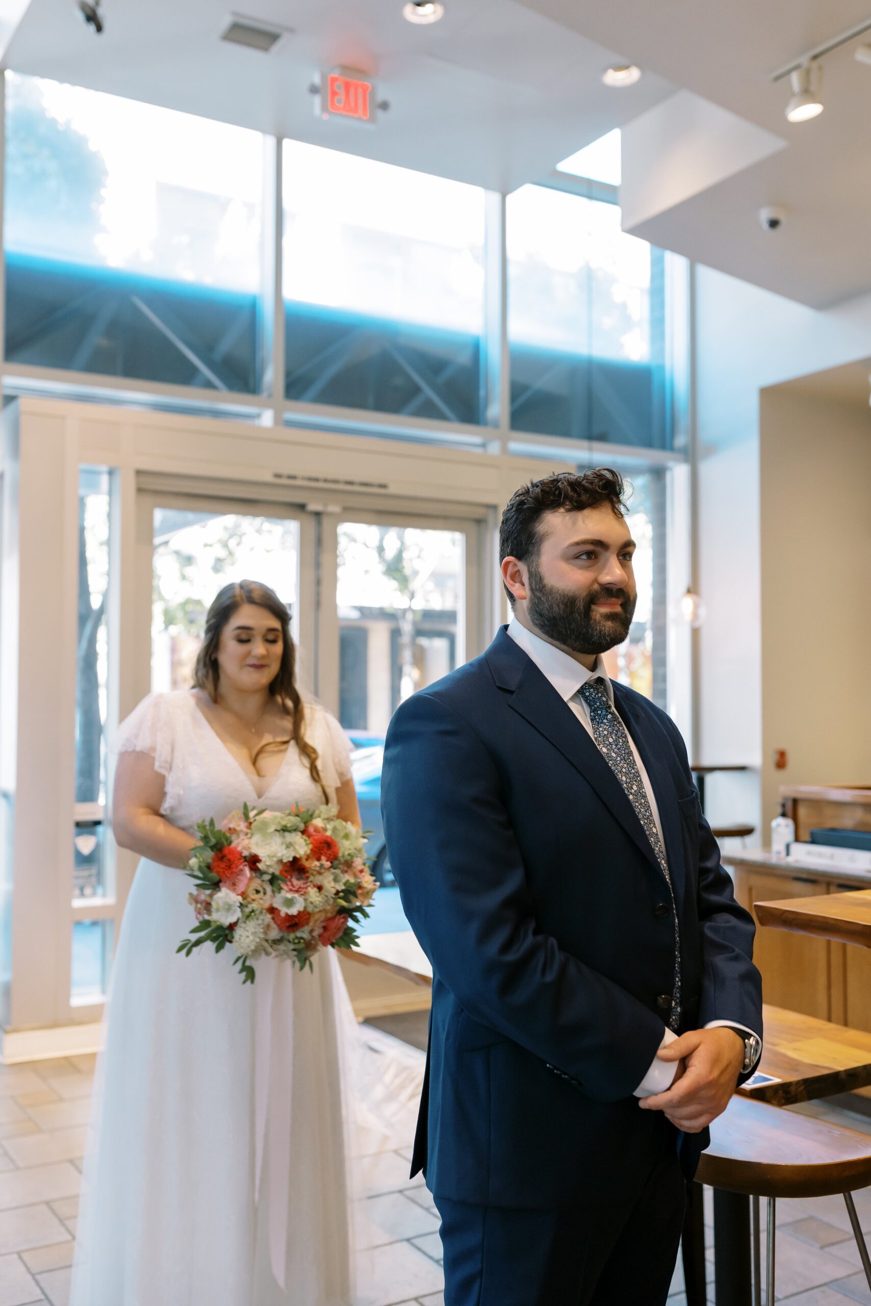  peet’s coffee shop first look elopement photos, woman holding bouquet and groom in navy blue suit 