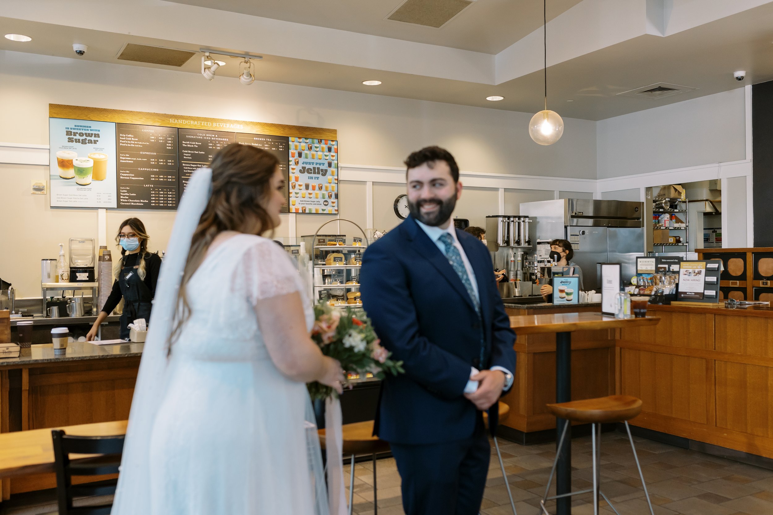  peet’s coffee shop first look elopement photos, woman holding bouquet and groom in navy blue suit 