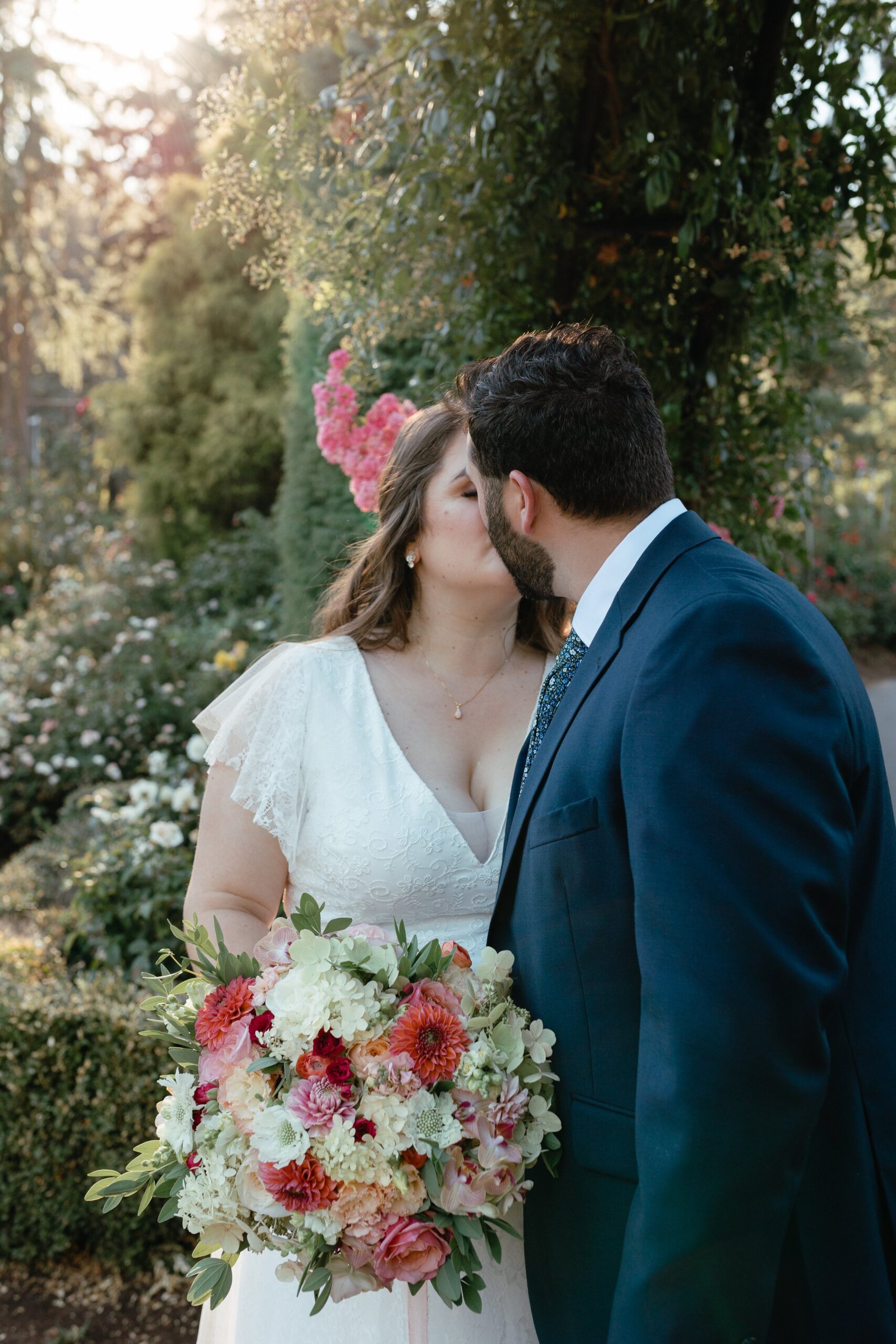  portland international rose garden elopement, couple holding elopement bouquet and kissing with flower arch  