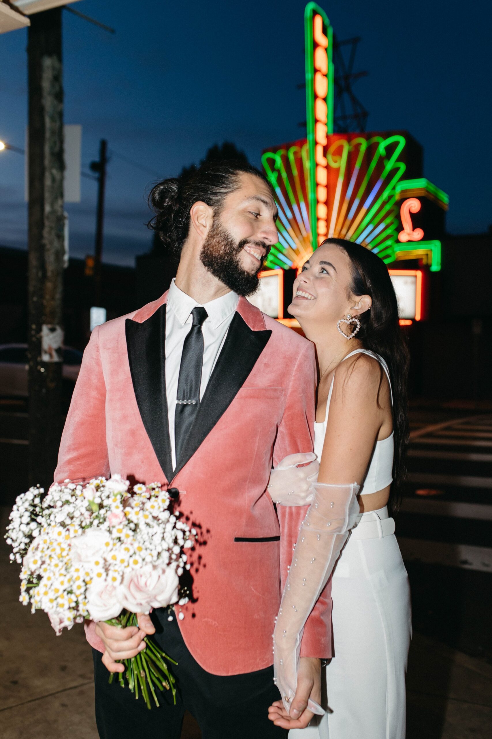  funky, modern, engagement photoshoot, neon signs, fun earrings, the unique couple poses, vegas inspired elopement nasty gal two-piece set, colorful suit, pearl gloves, movie theater, vintage, retro 