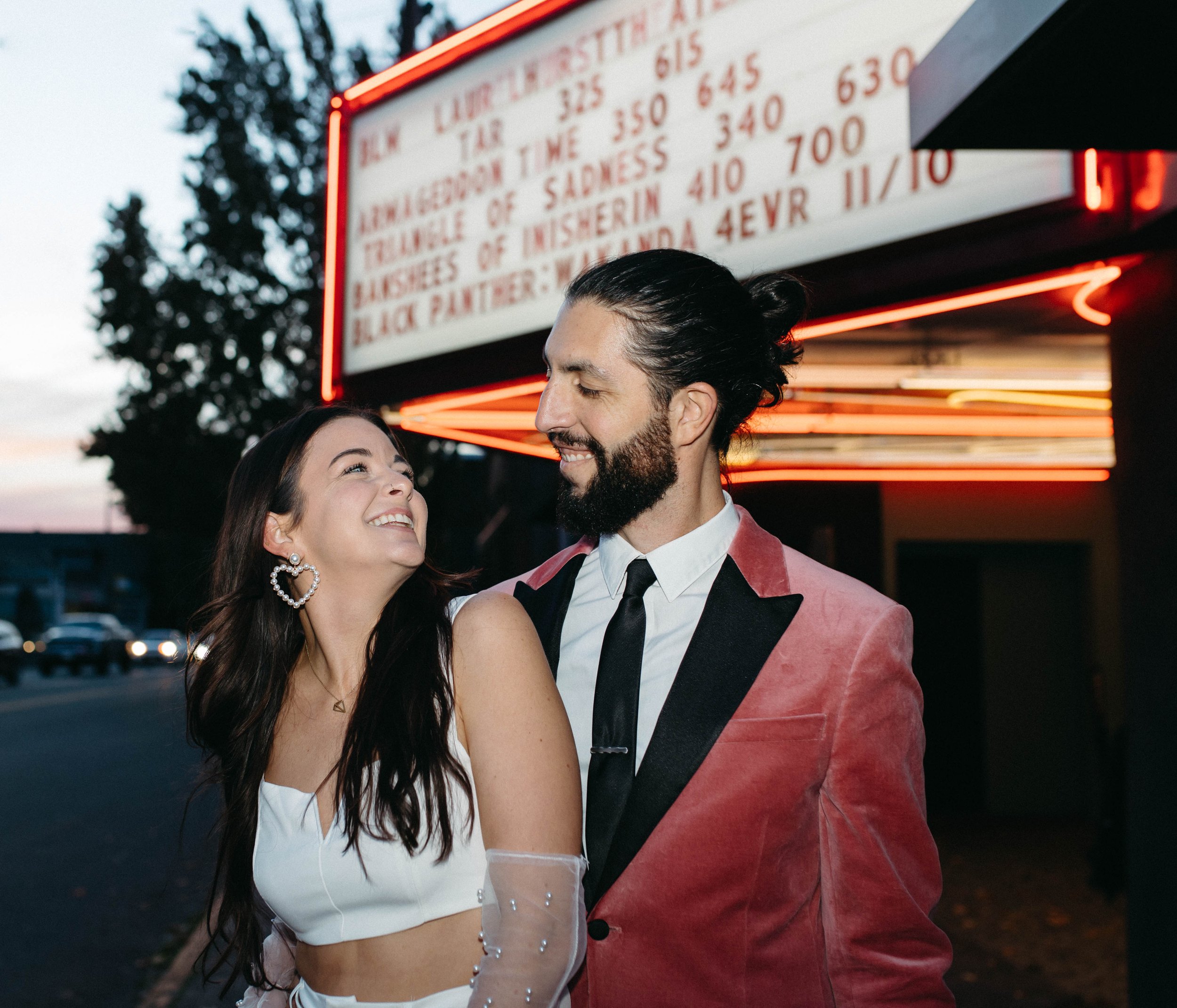  funky, modern, engagement photoshoot, neon signs, fun earrings, the unique couple poses, vegas inspired elopement nasty gal two-piece set, colorful suit, pearl gloves, movie theater 